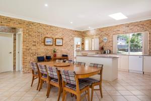 a kitchen and dining room with a wooden table and chairs at On The Lake - Pet Friendly Waterfront in Culburra Beach