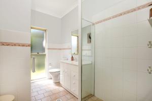a white bathroom with a toilet and a shower at On The Lake - Pet Friendly Waterfront in Culburra Beach +23 photos