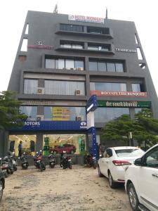 un grande edificio con macchine parcheggiate di fronte di Hotel Midnight a Ahmedabad