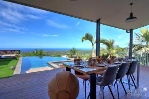 a dining table on a deck with a view of the ocean at VILLA KALAÉ in Étang-Salé