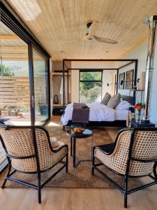 a bedroom with a bed and two chairs at Hemel 'N Aarde Stud in Hermanus