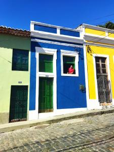 une personne qui regarde par la fenêtre d'une maison colorée dans l'établissement Casa Prudente, à Olinda