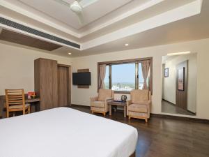 a bedroom with a bed and a desk and chairs at Pride Biznotel Sasan Gir in Sasan Gir