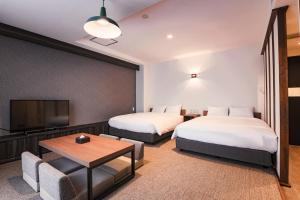 a hotel room with two beds and a flat screen tv at WAYFARER Shinsaibashi in Osaka