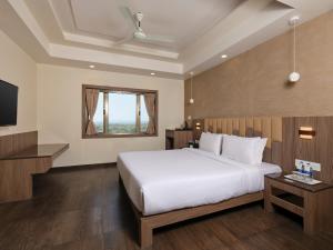 a bedroom with a large bed and a television at Pride Biznotel Sasan Gir in Sasan Gir