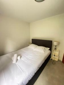 een slaapkamer met een bed met witte lakens en een lamp bij "Là-haut" free parking in Trois-Épis