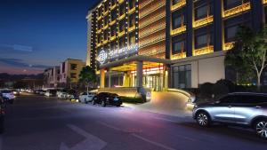 a building with cars parked in front of a street at Century Runhua Hotel in Jinan