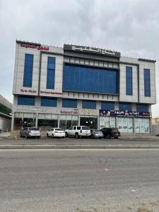 un grande edificio con macchine parcheggiate di fronte di تاج الخليج للشقق المخدومة a Dammam