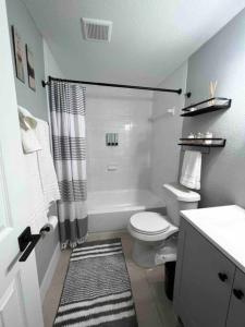 a white bathroom with a toilet and a shower at Busch Gardens Bliss Retreat 1 Bedroom in Tampa