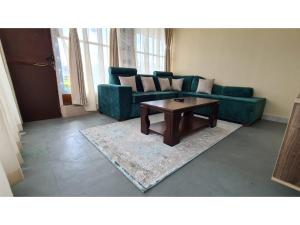 a living room with a green couch and a coffee table at Boffar Cabin 6 in Naivasha