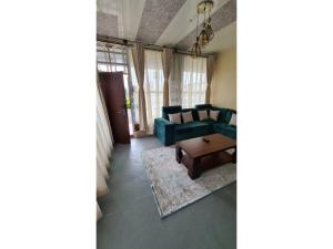 een woonkamer met een groene bank en een tafel bij Boffar Cabin 6 in Naivasha