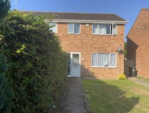 una casa de ladrillo con una puerta blanca y un seto en Canterbury 3BR close to shops with Free Parking, en Kent
