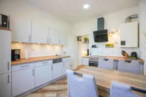 a kitchen with white cabinets and a wooden table at Ferienhaus Daheim in Borkum