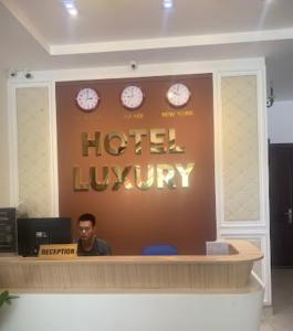 a man sitting at a hotel lobby with clocks on the wall at Luxury Hotel - 50/3 Trường Sơn, Q. Tân Bình - by Bayhostel in Ho Chi Minh City