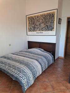 a bed in a room with a painting on the wall at Au cœur du Félibrige in Châteauneuf-de-Gadagne