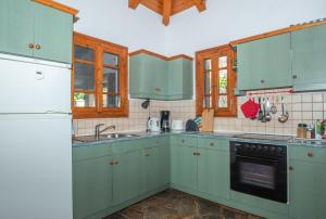a kitchen with green cabinets and a white refrigerator at Villa Dora in Tragaki +71 photos