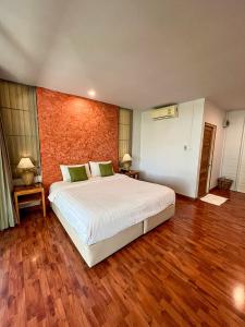 - une chambre avec un grand lit blanc et du parquet dans l'établissement ี เรือนปณาลี รีสอร์ท, à Ban Khlong Sai Yok