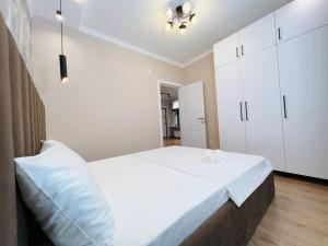 Schlafzimmer mit einem großen weißen Bett und weißen Schränken in der Unterkunft Central Park Apartment in Almaty