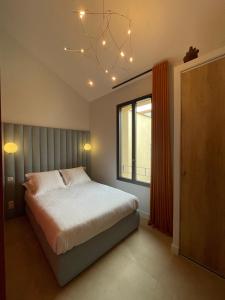 a bedroom with a bed and a window and a chandelier at Villa Chiesa in Le Grau-du-Roi