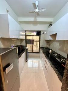 uma cozinha com armários brancos e uma ventoinha de tecto em La Valentine 1 BHK Apartment em Mumbai