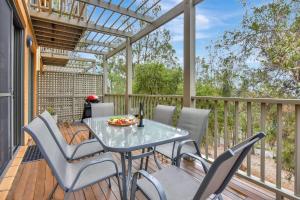 uma mesa e cadeiras num deque com uma pérgola em Villa 2br Nebbiolo Villa located within Cypress Lakes Resort em Pokolbin