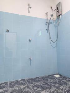 a shower in a bathroom with blue tiles at Manju Homestay in Sigiriya