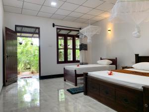 a bedroom with two beds and a window at Manju Homestay in Sigiriya