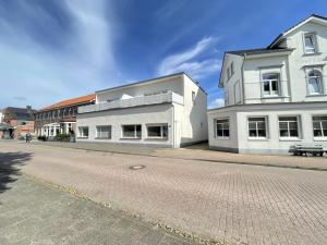 dos edificios blancos al lado de una calle adoquinada en Braganza, en Borkum
