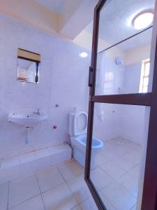 a white bathroom with a sink and a toilet at Calabash Hotel, Migori in Migori