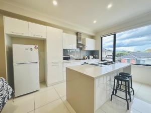 cocina con electrodomésticos blancos y ventana grande en Mt Waverley Spacious 2br2ba Parking Wifi Balcony, en Mount Waverley
