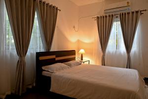 - une chambre avec un grand lit et des rideaux dans l'établissement YOGESH VILLA, à Vieux-Goa