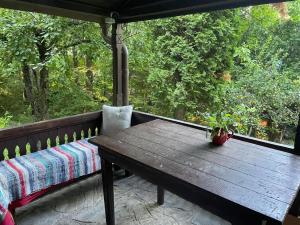 una mesa de madera y un banco en un porche en Nest in the Nature, en Brebu Megieşesc