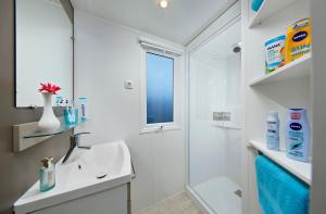 a white bathroom with a sink and a shower at KNAUS Campingpark Meppen in Meppen