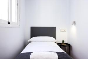 um quarto com uma cama com lençóis brancos e uma janela em Apartamentos turísticos Decumano Romano em Cartagena