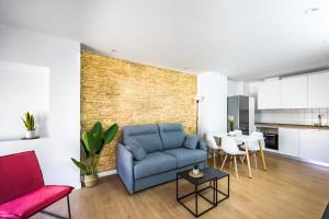 uma sala de estar com um sofá azul e uma parede de tijolos em Apartamentos turísticos Decumano Romano em Cartagena