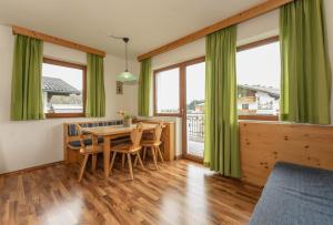 ein Esszimmer mit grünen Vorhängen sowie einem Tisch und Stühlen in der Unterkunft Gästehaus Sieder by Schladming-Appartements in Schladming