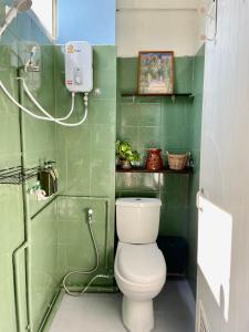 een groene badkamer met een toilet en een douche bij Baan KhaoSoi - Private room in a rooftop hostel 3rd floor in Khlong San