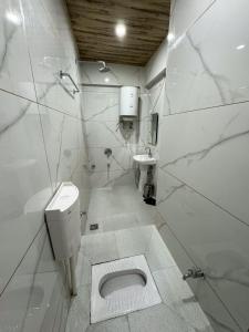 Baño blanco con aseo y lavamanos en Aasariya Hotel And Restaurants en Srinagar