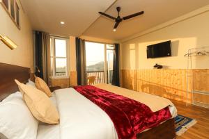 a bedroom with a bed with a red blanket on it at Himalayan Suite in Dharamshala