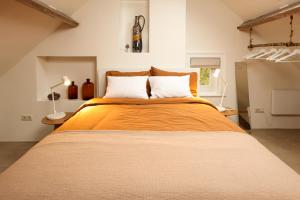 a bedroom with a large bed with an orange blanket at De Torteltuin in Nispen