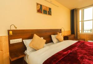 a bedroom with a large bed with a red blanket at Himalayan Suite in Dharamshala