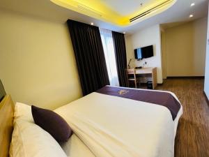 a hotel room with two beds and a desk at Azumaya Hotel Hai Phong in Hai Phong