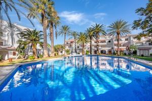 a large swimming pool with palm trees and buildings at Albatros 2 in Denia