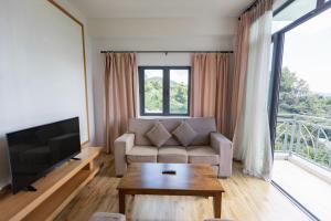 a living room with a couch and a large window at Hills Aranda Nova Hotel in Cameron Highlands