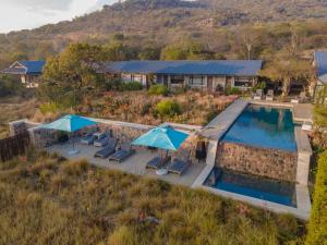 an overhead view of a swimming pool with chairs and umbrellas at Valley Lodge - Babanango Game Reserve in Dundee