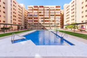 an empty swimming pool in a building with tall buildings at Ubicación Perfecta Apartamento Luxury Beach in Málaga