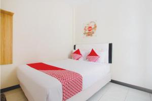 a bedroom with a white bed with red accents at SUPER OYO 3350 Cozy Residence Syariah in Malang