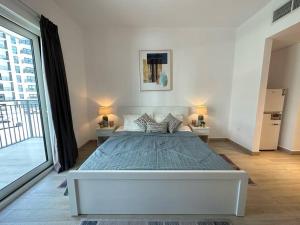 1 dormitorio blanco con 1 cama grande y 2 mesitas de noche en Comfy is just a holiday home! 105WB2, en Abu Dabi