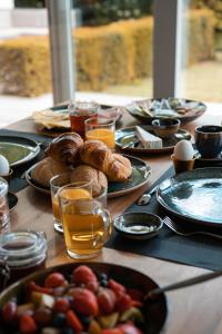 una mesa con platos de comida y vasos de zumo de naranja en Bed & Wellness Boxtel, luxe kamer met airco en eigen badkamer, ligbad, en Boxtel