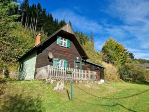 Casa de madera con ventanas verdes y valla en Rustic alpine hut in Vordernberg with sauna, en Vordernberg